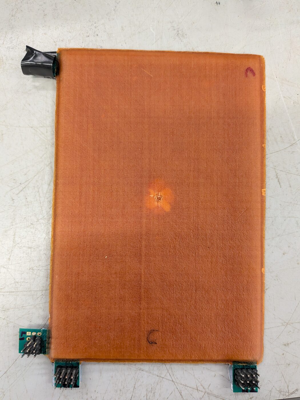 Finished plate after testing: a faint indent mark at the centre of the orange laminate